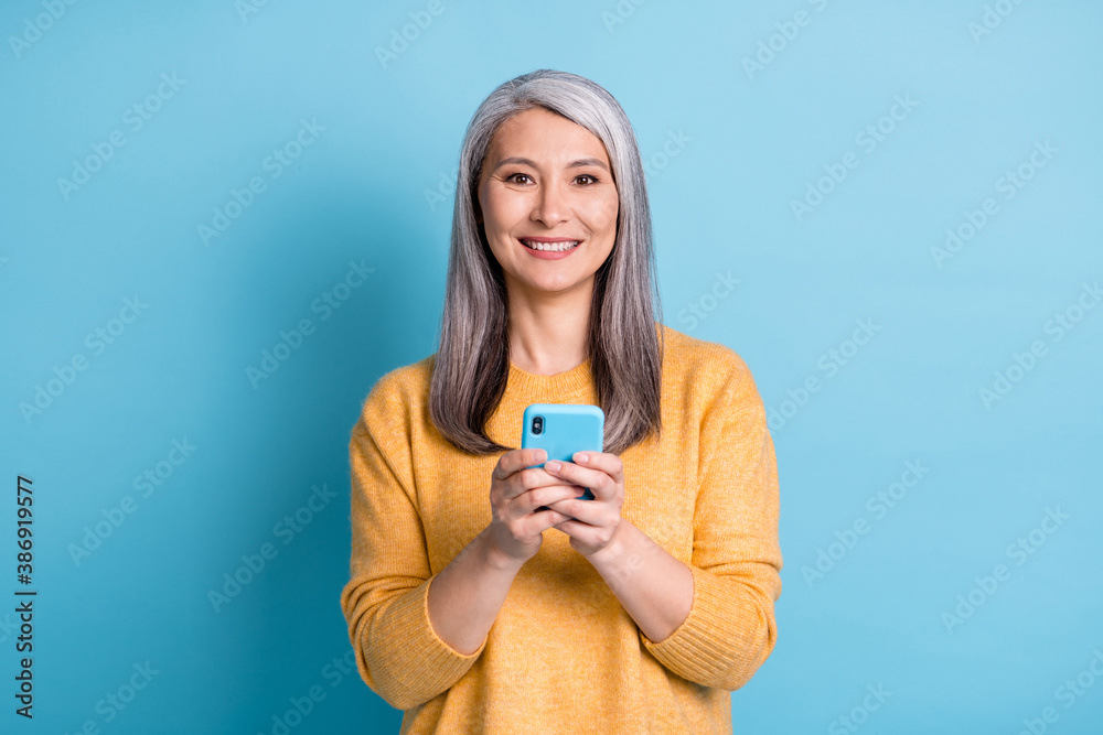 Photo of positive old woman use smartphone enjoy social network communication comment subscribe share news wear style stylish trendy sweater isolated over blue color background - obrazy, fototapety, plakaty 