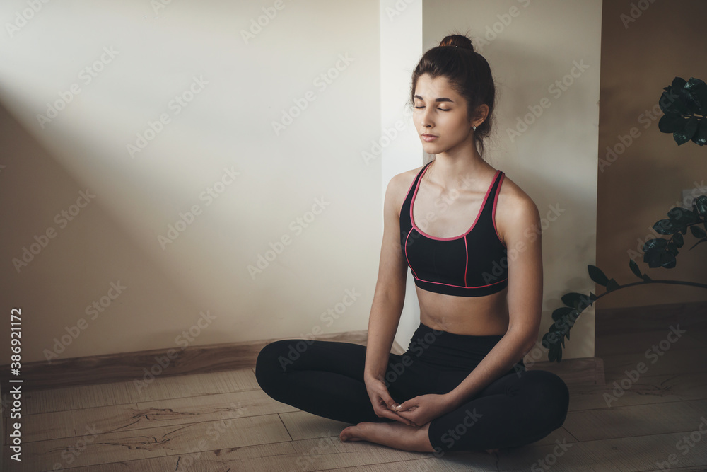 Fototapeta premium Caucasian woman in activewear is meditating on the floor while doing home gym exercises
