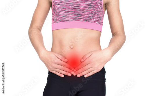 Young spotr girl suffering from atomach ache isolated on white background. Female person in sportswear with pain in stomach. Medical advertising concept with copy space.