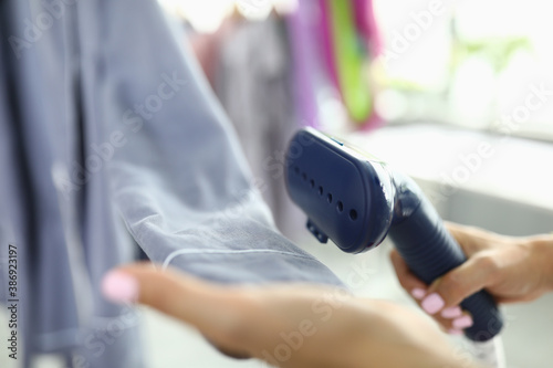 In hand of a steam steamer for clothes which iron sleeve. Steamers in daily use concept photo