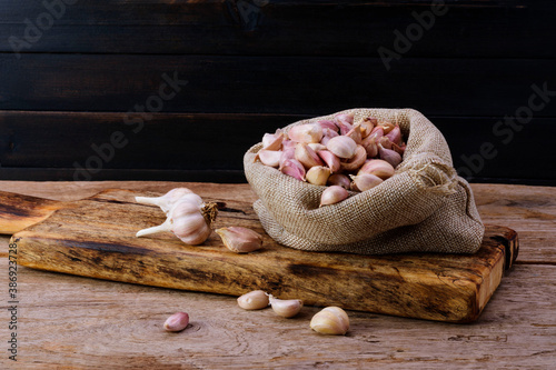 Garlic. Fresh garlic in sacks with cutting boards on an old wooden table. Black wood wall background.