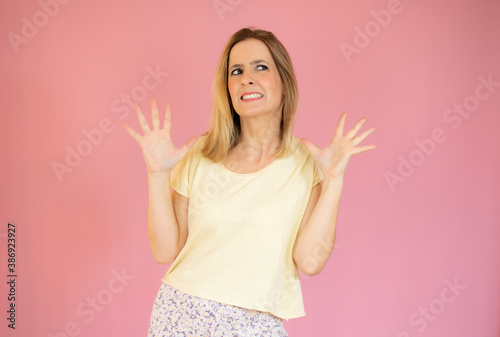 Young woman in nightwear making a rejection pose on a pink background