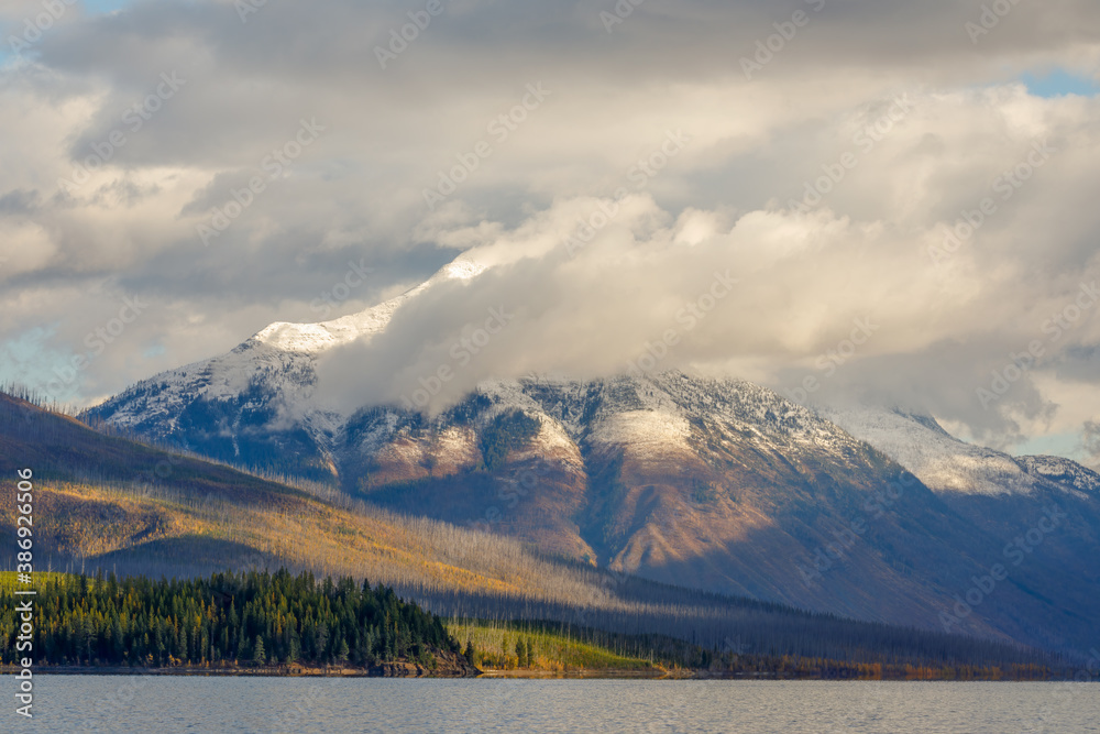 autumn landscape of majestic cloud enshrouded mountain in early morning with Lake McDonald in foreground, Glacier National Park, Montana autumn landscape of majestic cloud enshrouded mountain in early morning with Lake McDonald in foreground, Glacier National Park, Montana