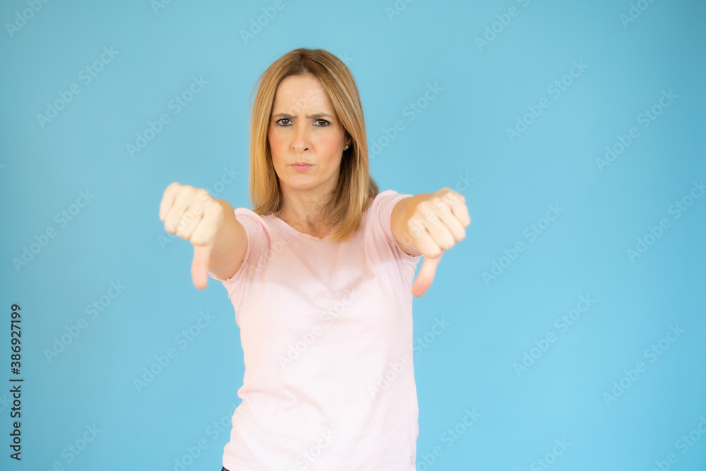 Fototapeta premium Portrait of displeased woman who is showing thumbs down