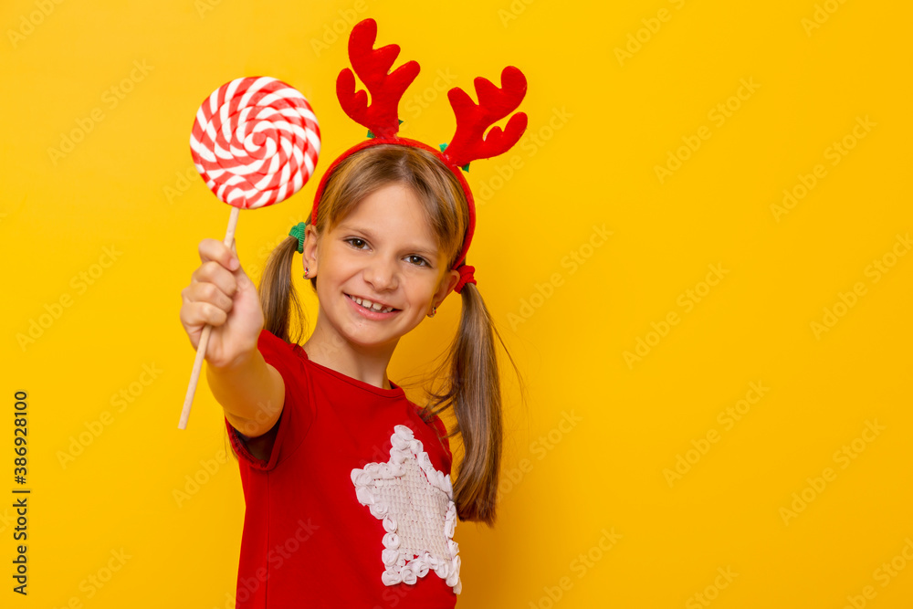 Kid wearing costume reindeer antlers holding lollipop
