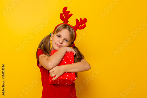 Little girl holding and hugging Christmas present