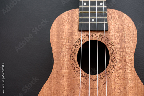 Brown ukulele on black background with shallow depht of field photo