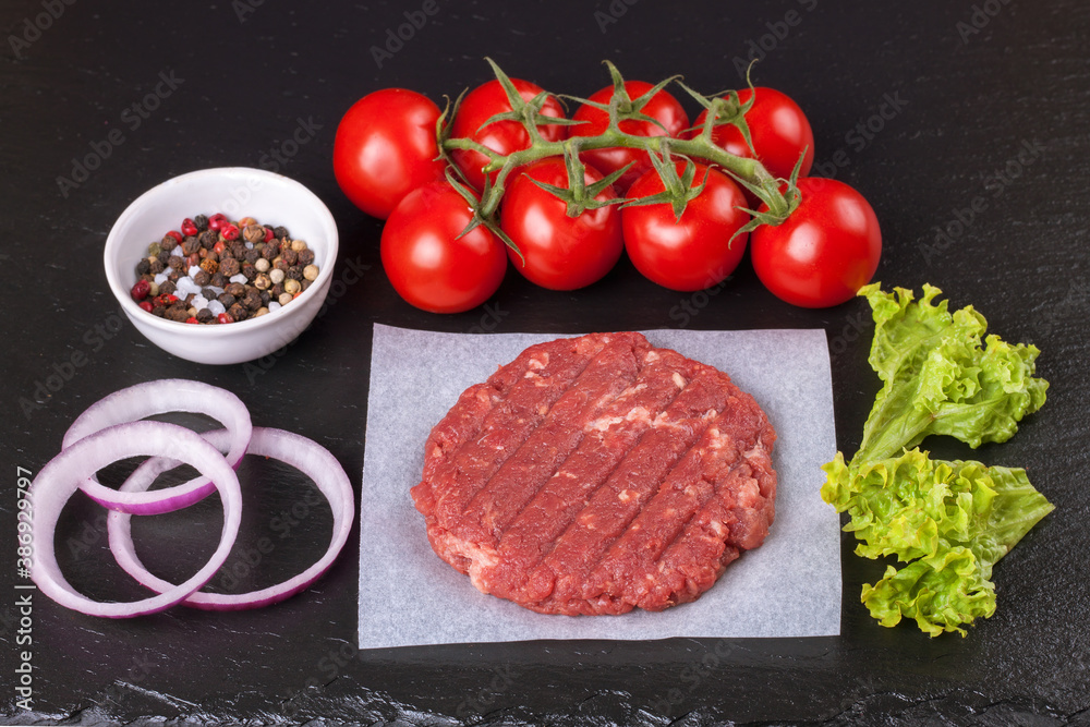 The raw ingredients for the homemade burger on black slate background. Top view. The raw ingredients for the homemade burger on black slate background. Top view.