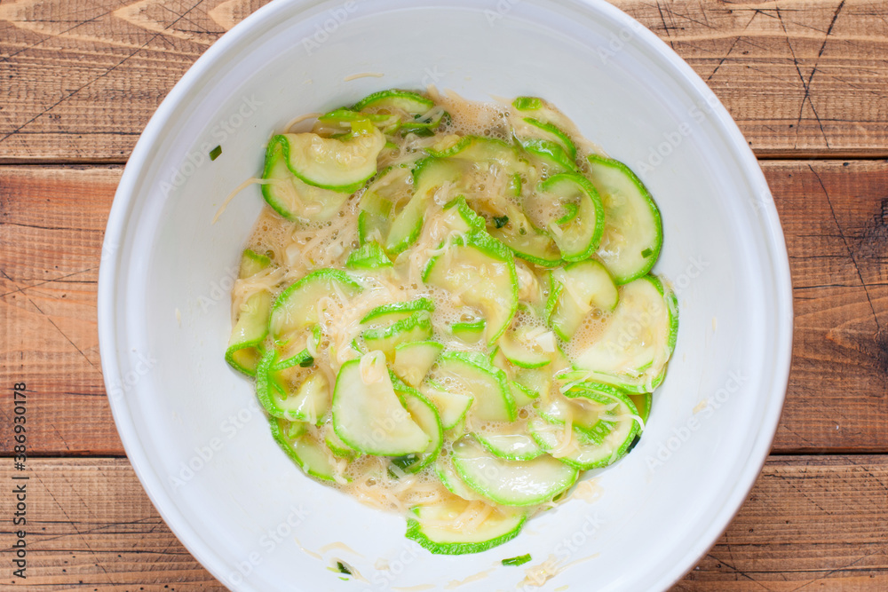 Cooking an open zucchini pie step by step, step 4 - preparing the filling - mixing the zucchini with cheese and egg, top view, horizontal Cooking an open zucchini pie step by step, step 4 - preparing the filling - mixing the zucchini with cheese and egg, top view, horizontal