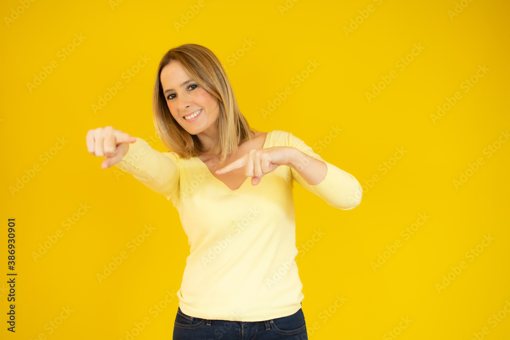 Portrait of attractive happy young woman pointing fingers over yellow background. Portrait of attractive happy young woman pointing fingers over yellow background.