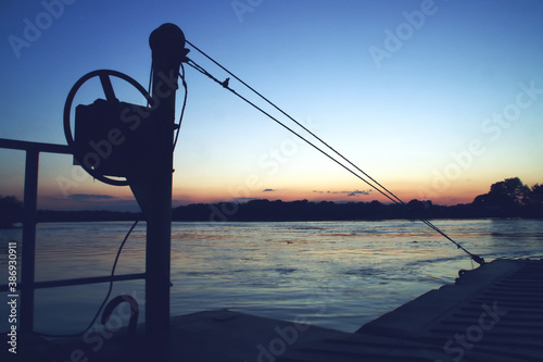 Barcaza de transporte fluvial al atardecer. Gabarra de carga en el delta del danubio a la puesta del sol en Nufaru, Rumanía. photo