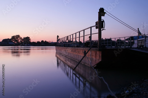 Barcaza de transporte fluvial al atardecer. Gabarra de carga en el delta del danubio a la puesta del sol en Nufaru, Rumanía. photo
