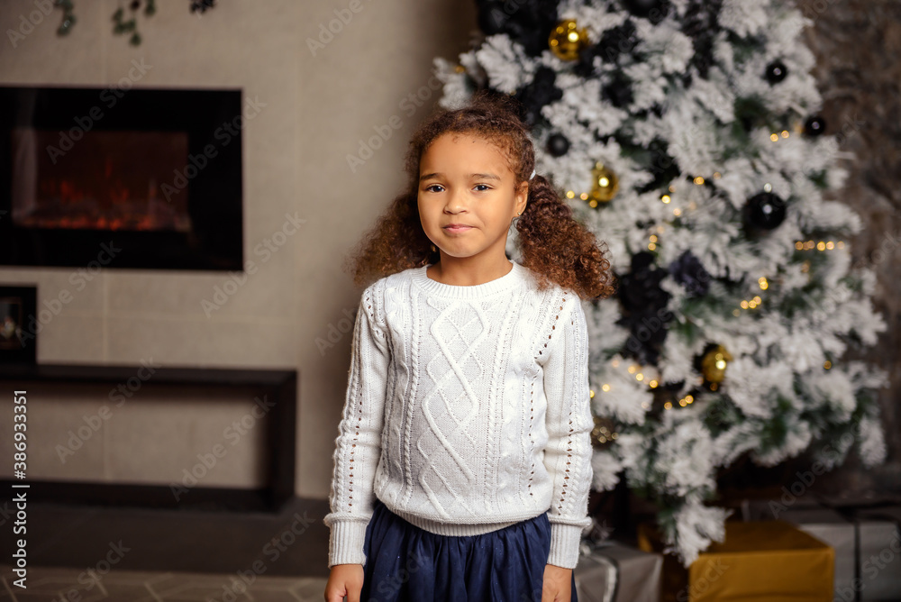 Beautiful little girl standing near Christmas in the New Year's interior. Beautiful little girl standing near Christmas in the New Year's interior.
