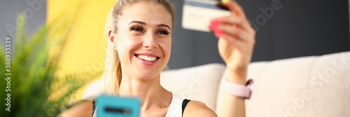 Beautiful woman looks at credit card and laughs
