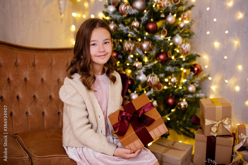 Christmas and childhood concept - cute little girl in decorated living room with Christmas tree, gift boxes and lights Christmas and childhood concept - cute little girl in decorated living room with Christmas tree, gift boxes and lights