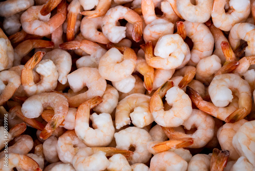 Close-up of a pile of frozen orange shrimps. Peeled shrimp, leaving only tails. Natural seafood background