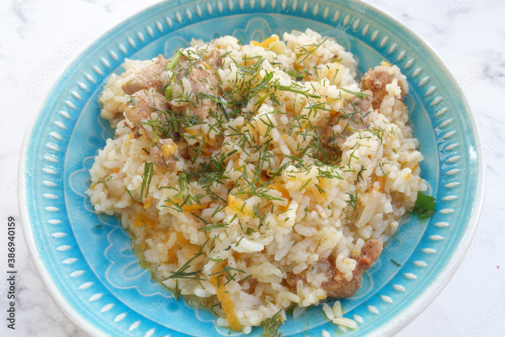 pilaf is a national dish. Rice with meat and fresh herbs is on the table, ready for a delicious dinner