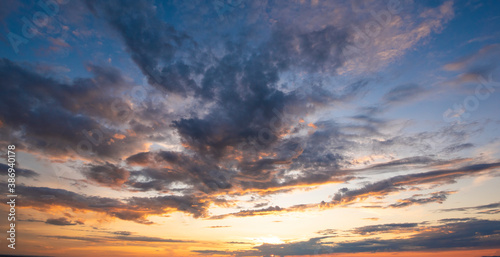 Sunset sky with clouds in blue and orange colors.