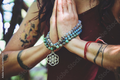 Konstfotografi Female hands doing namaste mudra yoga practice in forest with mala necklace