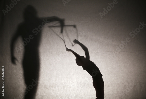 Shadow of woman silhouette holding a man like in a puppet show. Manipulation and dependence/control concept. Film edit. Selective focus. Copy space.