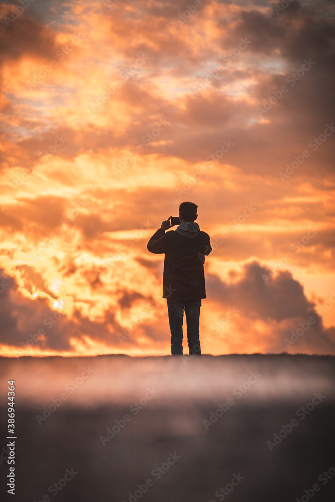 man on the background of the orange sky stands with his back