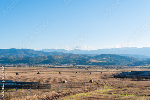 Massive hay field dry with a clear cut path mountain backdrop warm color bulgaria rural landscape sun day clear blue sky