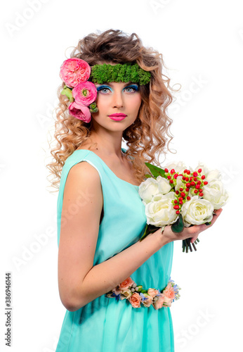 Young cute model with bright color makeup in a summer dress on a white background. Fresh flowers in the hairstyle