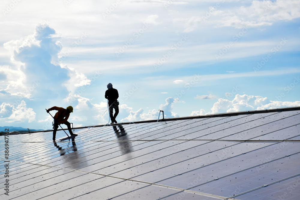 The workers of the photovoltaic company are spreading water and washing the surface of the solar panels which are so dirty with dust and pigeon's droppings on the roof in the afternoon of the day. The workers of the photovoltaic company are spreading water and washing the surface of the solar panels which are so dirty with dust and pigeon's droppings on the roof in the afternoon of the day.