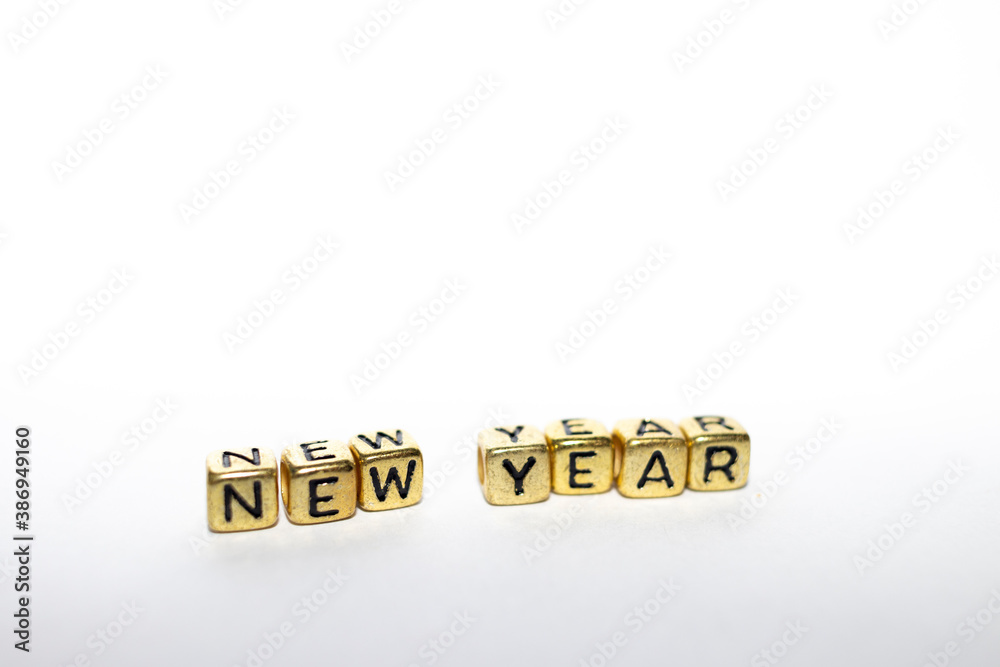 The word - New Year in the English alphabet made from yellow gold cubes on white. Christmas holidays concept. 2021 happy new year - lettering. The word - New Year in the English alphabet made from yellow gold cubes on white. Christmas holidays concept. 2021 happy new year - lettering.
