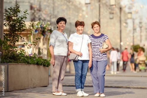 Mature Female Friends Socializing In Backyard Together.