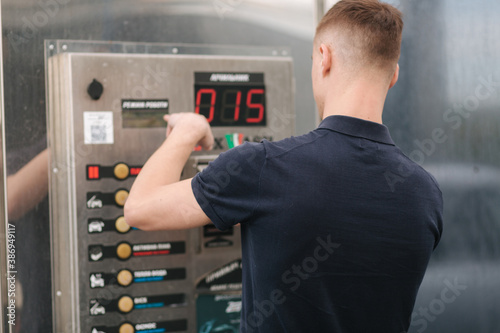 Male using self car washing. Man puts on the button on the machine