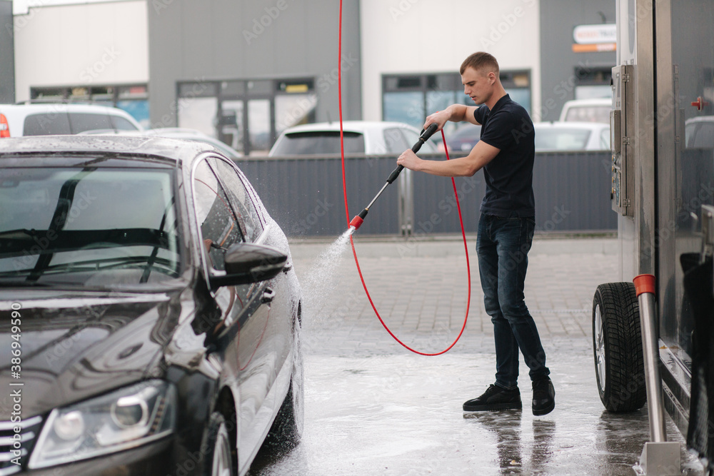 Cleaning car using active foam. Man washing his car on self car-washing