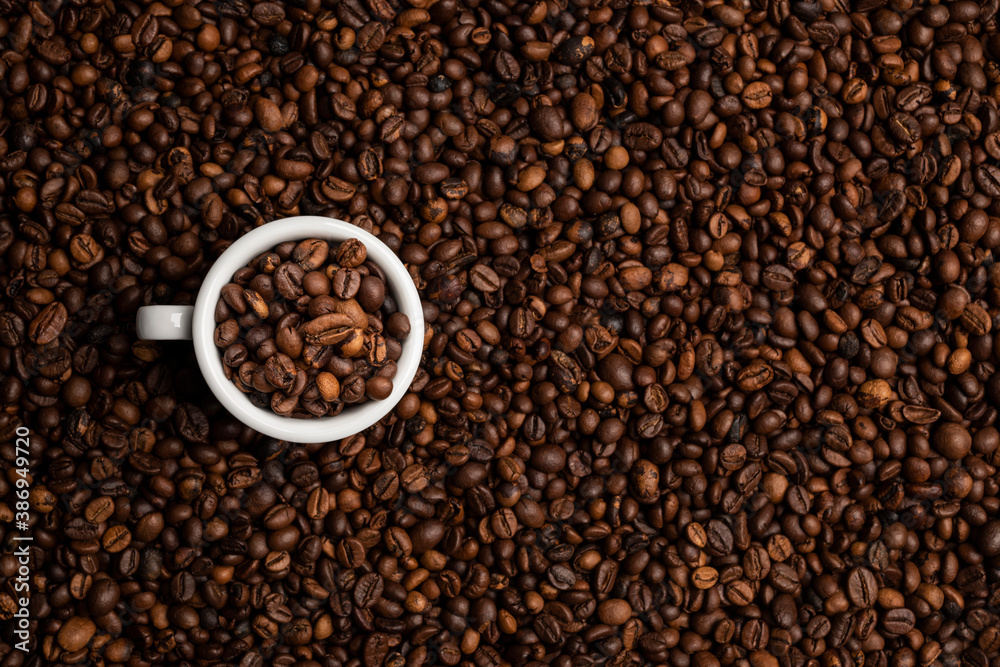 cup full of coffee beans over a background of coffee beans cup full of coffee beans over a background of coffee beans
