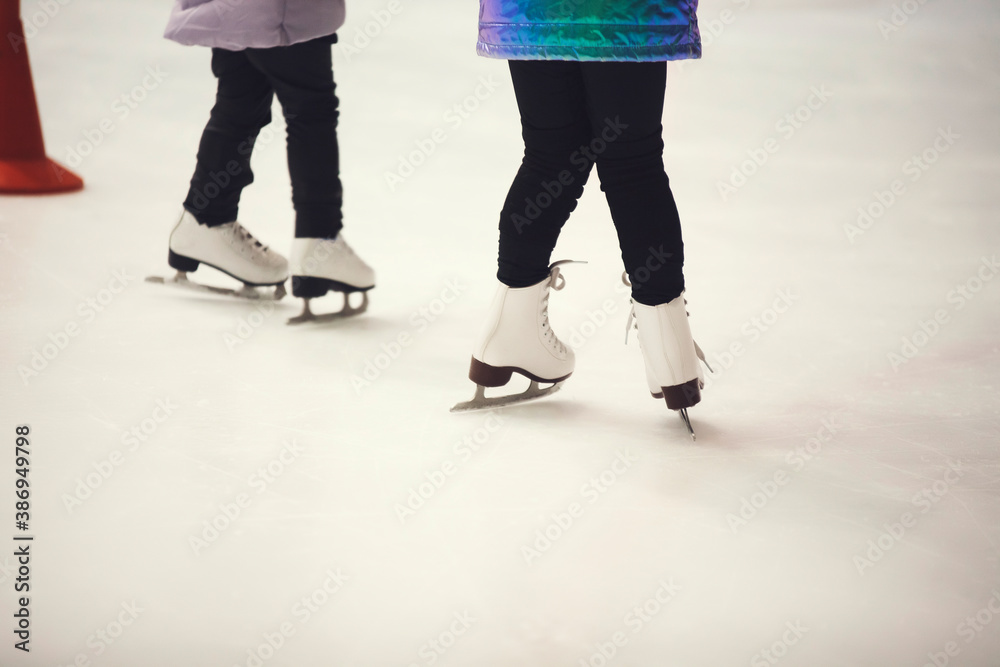 Figure skates on ice. Figure skating school. Young figure skaters practicing at indoor skating rink. Kid learning to ice skate. Figure skates on ice. Figure skating school. Young figure skaters practicing at indoor skating rink. Kid learning to ice skate.
