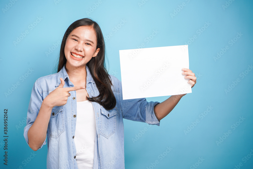 Pretty young woman holding empty blank paper and finger point for advertising banner on colorful background Pretty young woman holding empty blank paper and finger point for advertising banner on colorful background