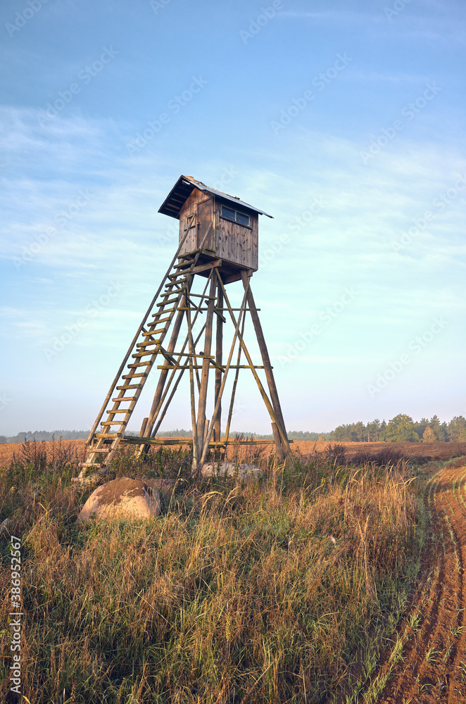 Naklejka premium Elevated wooden hunting blind on a field in early morning.