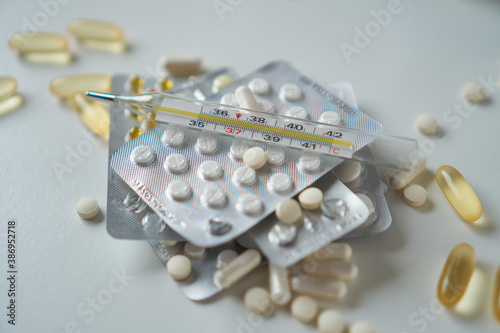Assorted pharmaceutical medicine pills, tablets and capsules with thermometer. 