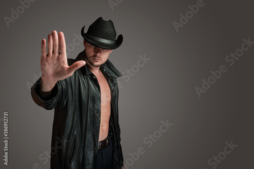 Cowboy in a leather coat makes a gesture of denial with his hand. Stop gesture. © kobzev3179