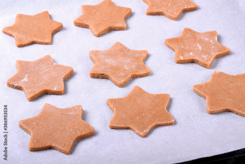 Star shaped dough for gingerbread shortbread cookies on the pastry parchment ready to be baked Star shaped dough for gingerbread shortbread cookies on the pastry parchment ready to be baked