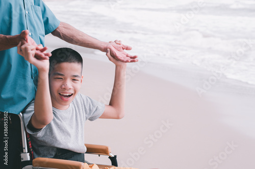 Asian special child on wheelchair is smiling, playing and doing activity on the sea beach, Lifestyle of disability child, Life in the education age, Happy disabled kid in travel holidays concept.
