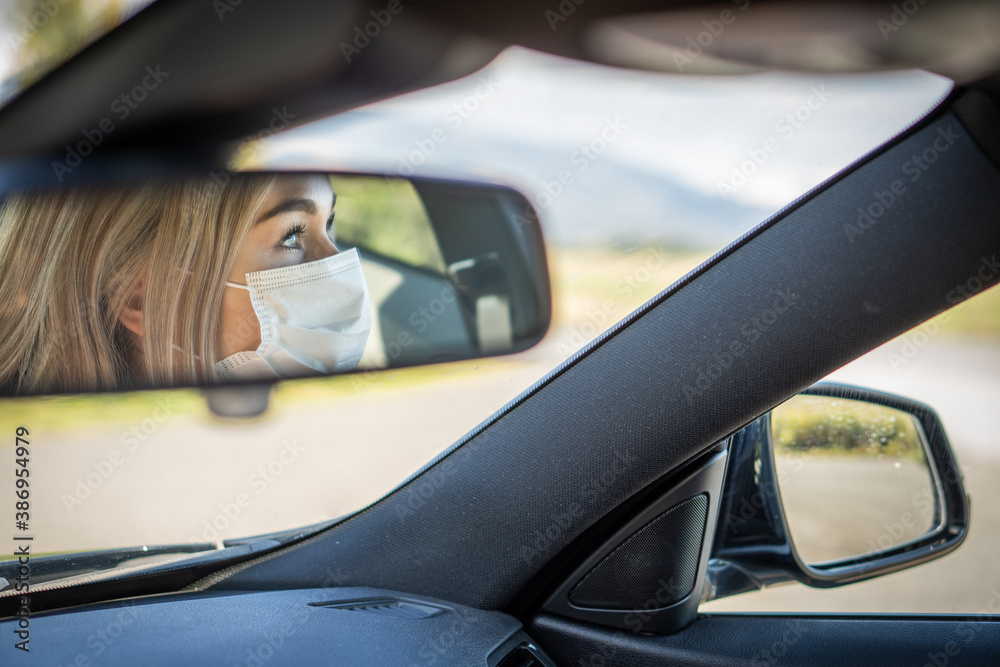 Young woman driving car with protective mask on her face. Young woman driving car with protective mask on her face.