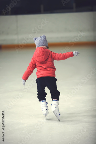 Figure skating school. Young figure skater practicing at indoor skating rink. Kid learning to ice skate. photo