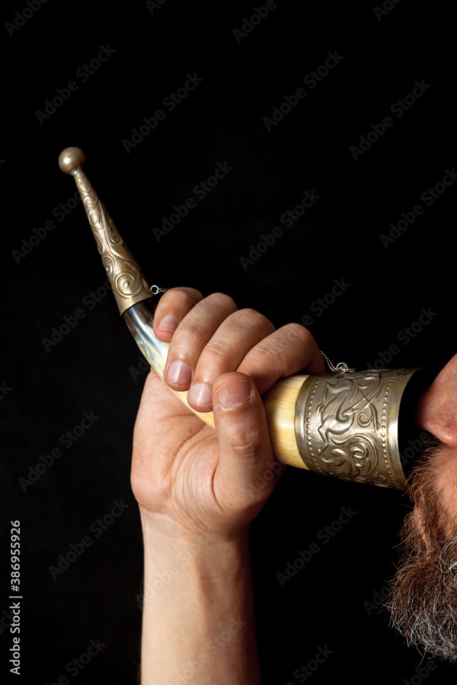 Man with beard drinks from horn on black background Man with beard drinks from horn on black background