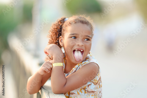 Very funny cute little girl showing tongue, with pigtails, summer, outdoors, concept childhood