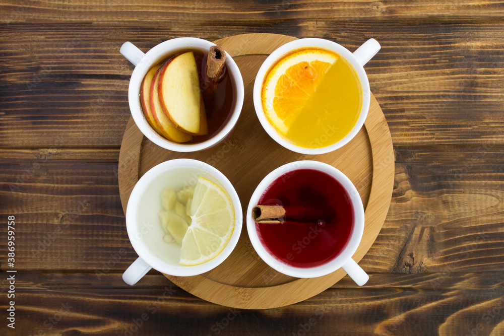 Top view of different teas in the white cups on the round wooden cutting board Top view of different teas in the white cups on the round wooden cutting board