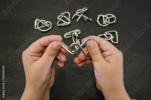 metal puzzle in hands. Black background. Close-up. Concept to solve the puzzle. photo