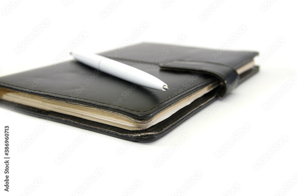 black notepad and white pen on a white background. Close-up. black notepad and white pen on a white background. Close-up.
