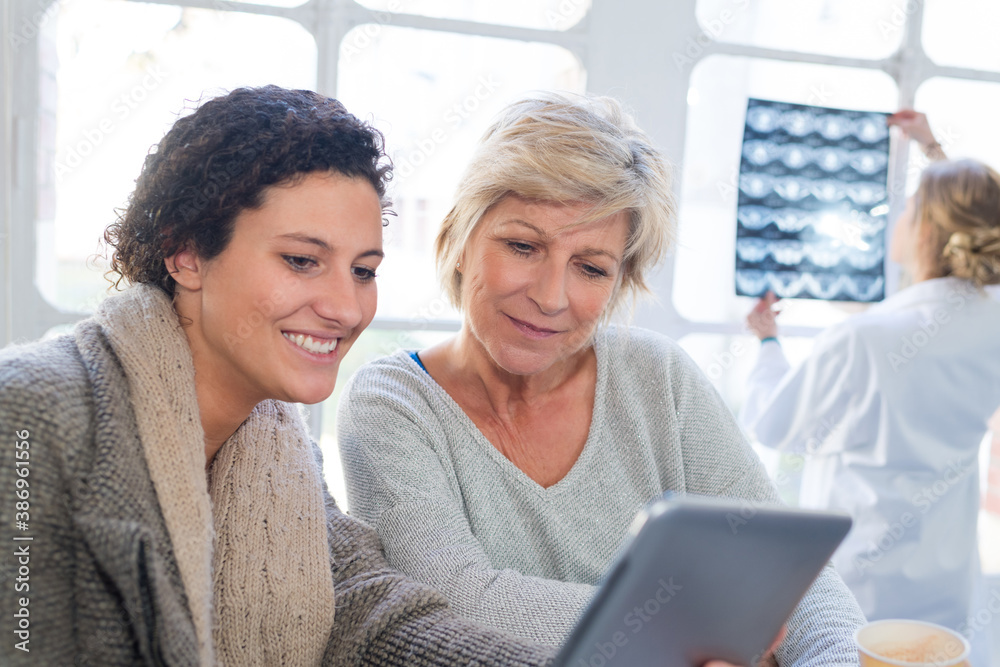 patients looking at tablet and doctor in the background