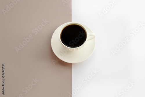 White porcelain cup with black coffee on the beige texture and white background. Simple template for your postcard and design, place for text, flat lay