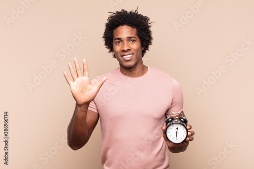 Cuadro en lienzo young black afro man smiling and looking friendly, showing number five or fifth